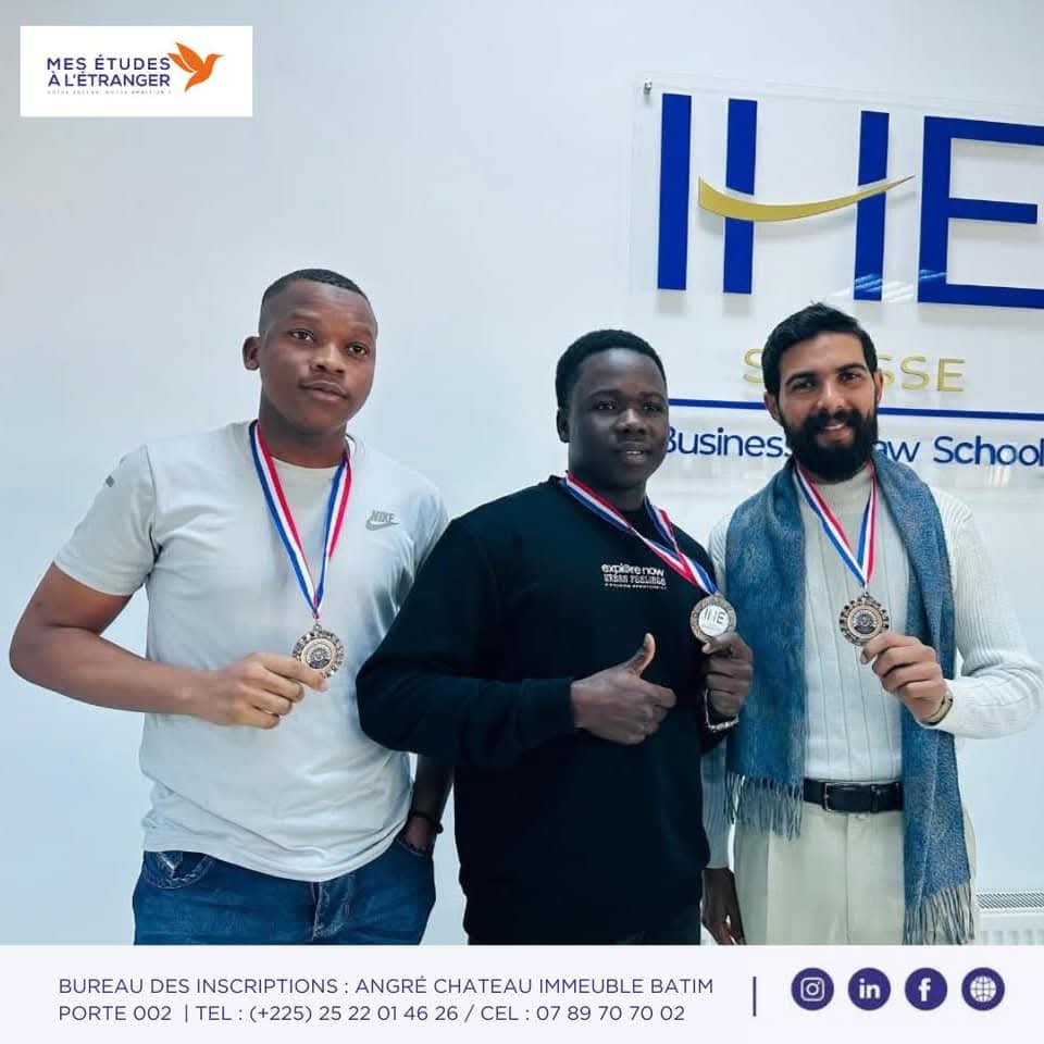 Trois étudiants médaillés posant ensemble devant le logo IHE Sousse